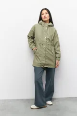 Piloto verde militar de manga larga con capucha y forro de color amarillo. Cuenta con dos bolsillos laterales con solapa, cordones ajustables, elástico en los puños, cierre y botones metálicos.