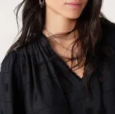 Blusa negra con bordados geométricos, escote en V con cordones y mangas largas.