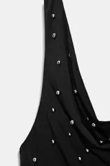 Top halter negro con escote drapeado tipo cascada y espalda descubierta. La prenda está adornada con pequeños apliques brillantes distribuidos por toda la tela y presenta un bajo asimétrico.