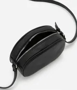 Cartera tipo camera bag pequeña, color marrón camel, de forma ovalada con superficie texturizada. Cuenta con correa ajustable larga, cierre principal con cremallera dorada y un pequeño bolsillo frontal con cremallera.