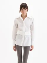 Camisa Oslo de poplín de algodón color blanco, con silueta estructurada, cuello camisero amplio, manga larga y cinturón ancho incorporado con hebilla rectangular forrada.