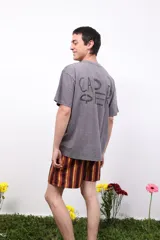 Remera gris de algodón con efecto acid wash, cuello redondo y mangas cortas. Presenta un pequeño logo estampado en el pecho y un estampado más grande en la espalda.