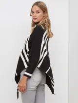 Poncho de tejido color beige con cuello alto y rayas diagonales anchas en azul marino. Presenta mangas largas y terminación asimétrica.