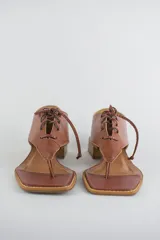Sandalias de cuero color beige con diseño de ojota acordonada en el empeine, puntera cuadrada y taco bajo cuadrado.
