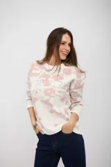 Buzo de tejido de punto con diseño estampado floral en tonos rosa y gris sobre base color crudo. Presenta cuello redondo y mangas largas con puños ajustados.
