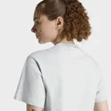 Remera Adidas de algodón en color gris jaspeado, con cuello redondo, mangas cortas y logo de la marca bordado sutilmente en el centro del pecho.