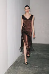 Vestido midi marrón con bordados florales y geométricos en el frente, escote redondo, mangas sisa, tejido plisado y flecos en el ruedo.