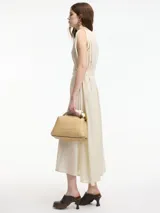 Vestido midi de algodón color crudo, con diseño tipo túnica, cuello redondo y lazo ajustable en la cintura para entallar la silueta. Presenta detalles de bordado sutil en el cuello y las sisas.