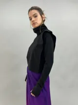 Buzo de jersey de lana color negro, con cuello elevado, hombreras estructuradas y mangas largas con puños con ojal para el pulgar.