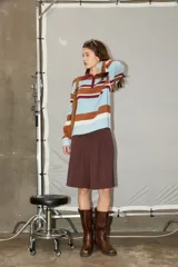 Sweater de tejido de punto con diseño de rayas horizontales en tonos marrón, celeste y bordó. Presenta cuello tipo polo con cierre frontal, mangas largas y corte holgado.