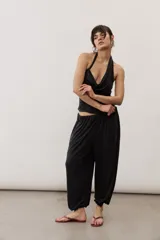 Pantalón holgado negro tipo bombacho, con cintura elástica y puños fruncidos en los tobillos.