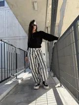 Pantalón de jean con diseño de rayas verticales en tonos gris y blanco, de corte ancho y relajado.