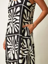 Vestido midi negro con estampado gráfico en blanco, de corte amplio y escote redondo con tirantes anudados en los hombros.