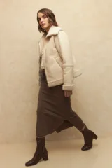 Campera gamulán negra con cuello, puños y ruedo de corderito. Tiene cierre frontal con cremallera y bolsillos laterales.