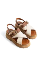 Sandalias de cuero combinadas en tonos marrón y marfil, con tiras cruzadas en el empeine, suela chunky con plataforma dentada y tira ajustable con hebilla metálica en el tobillo.