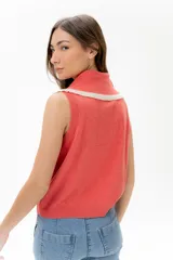 Chaleco de punto sin mangas, color azul marino, con cuello y frente adornados con volados en contraste de color blanco o crudo.