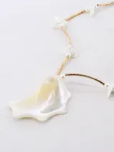 Collar de cadena dorada con dije central de nácar irregular y detalles de pequeñas cuentas blancas.
