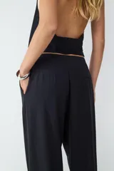 Pantalón negro de tiro medio, confeccionado en tejido fluido, de pernera recta con pinzas delanteras y cierre frontal oculto.