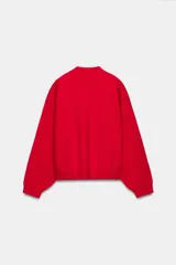 Sudadera de punto lisa en color rojo, con cuello subido y manga larga. Presenta un diseño de corte holgado con acabados en rib en puños y ruedo.