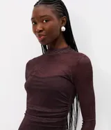 Vestido midi de tul con estampado sutil, de corte ajustado, cuello alto y mangas largas. Presenta un diseño con transparencias y forro interno parcial.