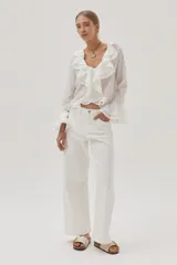 Blusa blanca de gasa con lunares, escote en V con volados y mangas largas acampanadas.