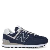 Championes urbanos New Balance modelo 574, color azul marino con detalles en gris y blanco. Confeccionados en una combinación de gamuza y malla, presentan el logo 'N' característico en los laterales, lengüeta con etiqueta de la marca y entresuela con tecnología ENCAP para mayor amortiguación.