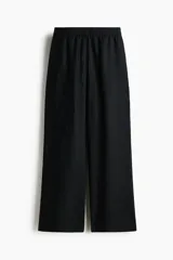 Pantalón de corte holgado en tejido liviano de mezcla de lino, con tiro alto, cintura elástica y cordón ajustable, bolsillos laterales y piernas rectas.