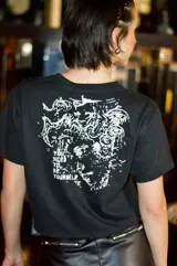 Remera negra de manga corta y cuello redondo con detalles en tachas, efecto lavado desgastado y estampado frontal.