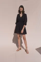 Vestido corto negro de broderie de algodón, con escote en V, mangas tres cuartos, cintura elastizada, falda corte A con volado y forro interior.