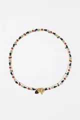 Collar de doble cadena dorada compuesto por una cadena de eslabones finos y una hilera de cuentas de granito en colores negro, rojo, verde y blanco. Incluye un cierre de barra y aro y un dije en forma de corazón esmaltado en negro.