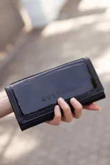 Billetera mediana Austera de cuero negro charolado con broche. Hecha a mano en Uruguay.