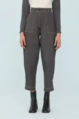 Pantalón gris de corte cropped, con pinzas, costuras a contratono y tablas en los laterales sostenidas con cuatro botones.