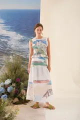 Falda larga de corte evasé, confeccionada en tela liviana de base blanca con un estampado artístico de paisajes en tonos celestes, verdes y rosados.