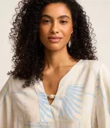 Blusa de manga corta en viscosa color beige, con escote en V con detalle de tira y cuenta de madera, y estampado geométrica y de follaje en tonos celestes.