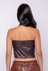 Top negro al cuerpo sin mangas, con cuello halter cruzado, cut out en el escote y confeccionado en tela metalizada de textura diferenciada.