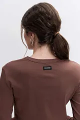 Remera de manga larga en color marrón, con cuello redondo y corte ajustado al cuerpo.
