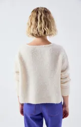Sweater de punto fino en color beige, con escote en V, mangas largas y corte holgado.