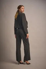 Pantalón de vestir negro con brillo, tiro medio, corte ajustado y ruedo amplio con tajos laterales.