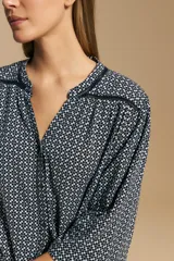 Camisa de manga larga con silueta relajada, estampado a rayas verticales en blanco y gris, escote abierto con botones frontales y puños elastizados.