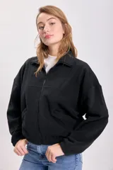 Campera de polar negro con cierre frontal, cuello alto, bolsillos laterales y corte holgado.