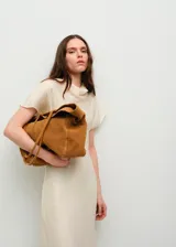 Bolso de piel bovina en color tostado, con diseño tipo duffel y correas dobles ajustables.