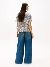 Remera de manga corta con cuello redondo ribeteado en azul marino. Presenta un estampado integral de cachemira (paisley) en tonos azul marino y blanco crema.