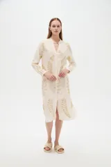 Vestido midi holgado de viscosa color beige, con mangas largas, cuello mao, cierre frontal con botones y detalle de bordado con lurex con diseño de hojas doradas.