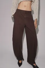 Pantalón cargo de tiro medio confeccionado en algodón, con diseño de pierna tipo barril. Presenta bolsillos laterales y bolsillos de plastrón con solapa en las piernas, además de un bajo ajustable con trabillas y hebilla metálica.