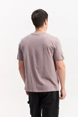 Remera de manga corta color gris topo, con cuello redondo y estampa frontal de estilo urbano con texto en tono claro.