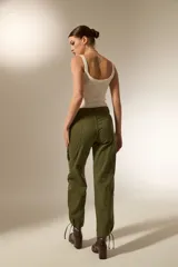 Pantalon cargo de algodón color gris oscuro, de tiro alto y corte recto. Presenta bolsillos laterales tipo cargo y una hilera de ojales metálicos decorativos a lo largo de la pierna derecha.