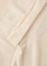 Jersey de punto fino color beige, con cuello alto y mangas largas de diseño recto.