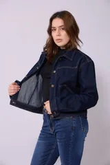 Campera de jean de mujer, color azul claro lavado, con corte cropped y estilo clásico. Presenta cuello camisero, botones metálicos frontales y bolsillos de parche en el pecho.