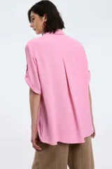 Camisa blanca de manga corta con puños doblados, cuello clásico y cierre frontal de botones.