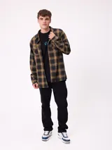 Camisa de manga larga confeccionada en franela de algodón, con diseño de cuadros en tonos verde y marrón. Presenta cuello clásico, cierre frontal con botones y dos bolsillos en el pecho con solapa.